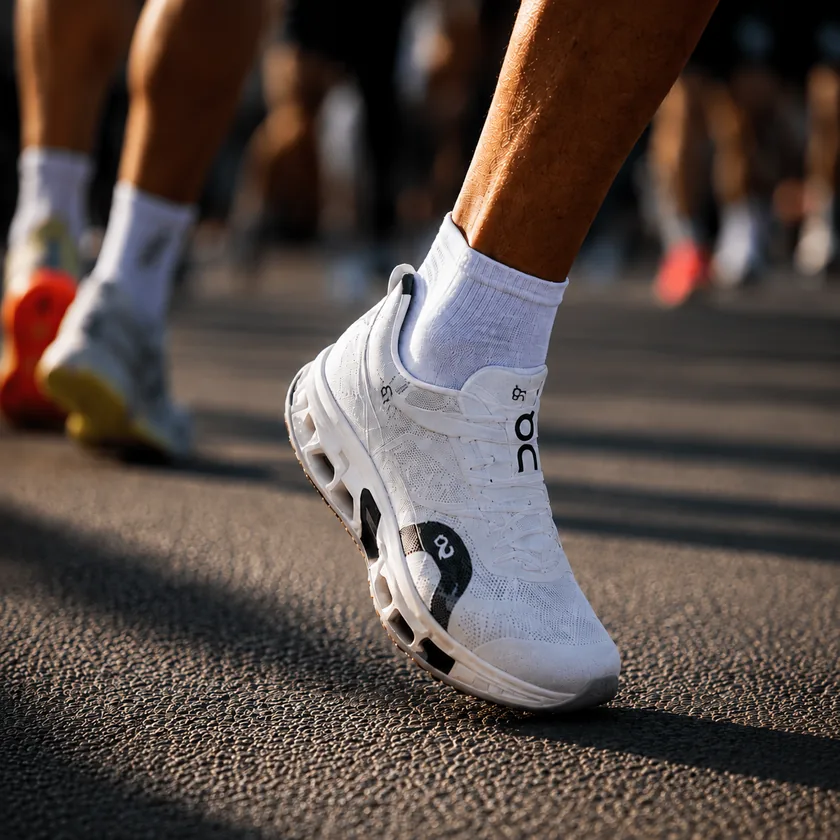 A runner's white On shoe mid-stride on asphalt, ringed by a hexagon the way RunnerTag marks what its AI has identified.