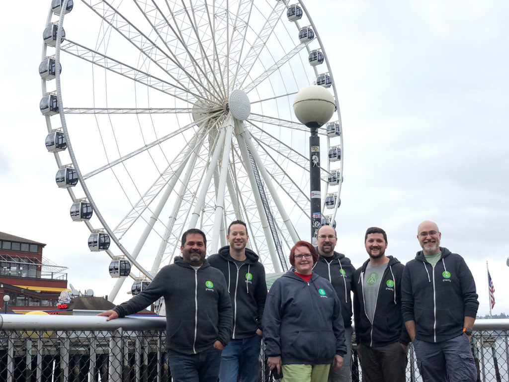 The Greenfly Seattle team taking in the city sights, standing together for a group photo in front of the Seattle Great Wheel.