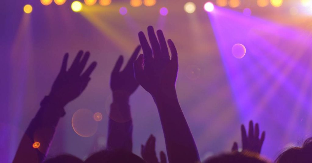 Silhouette of concert-goer hands in air