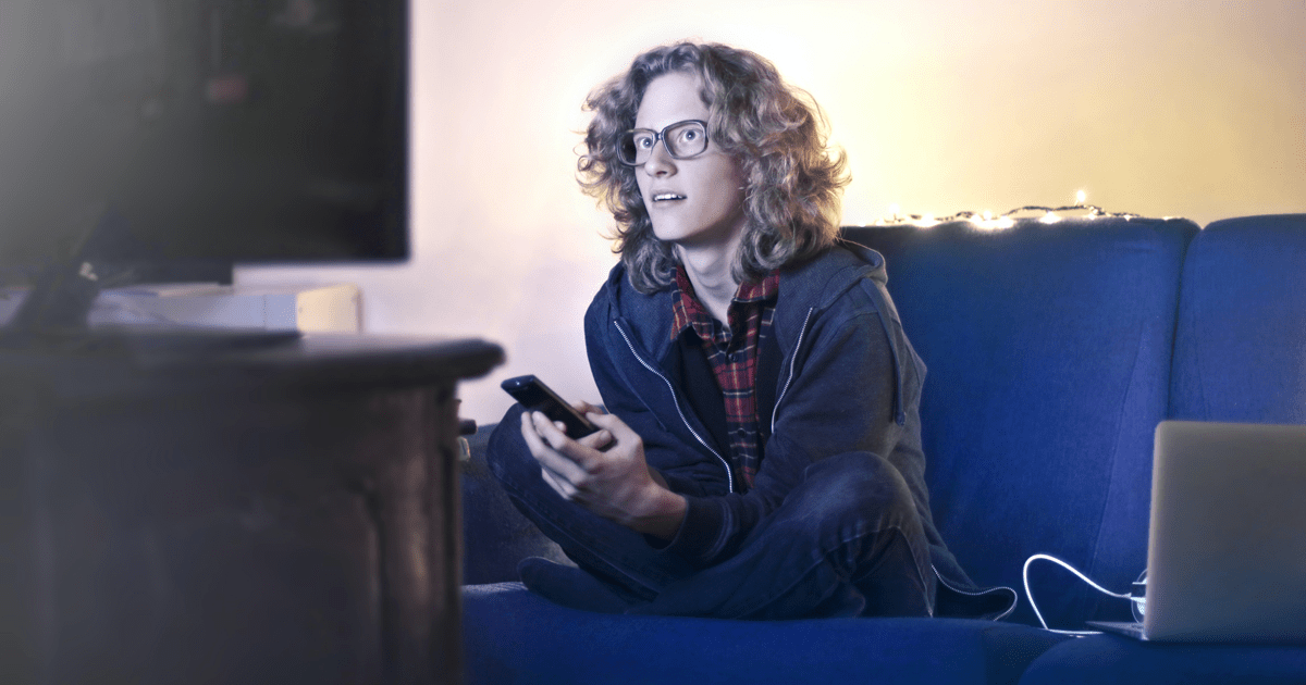 young male watching tv with mobile devices