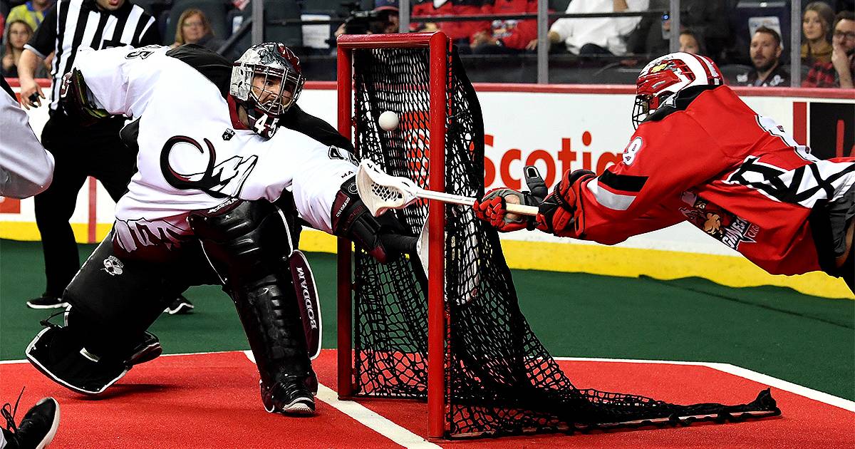 Two opposing NLL player at goal during game.
