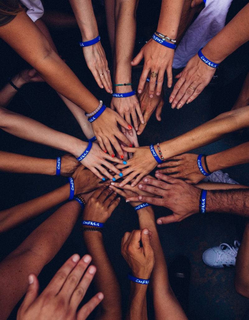 Closeup shot of a group of people joining their hands together in a huddle