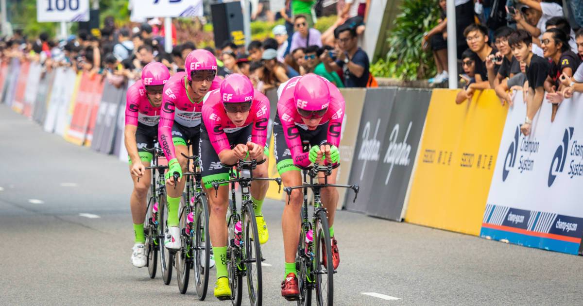 Using social media for athletes and how to improve your reach - bicycle riders in race wearing pink uniforms ride past fans