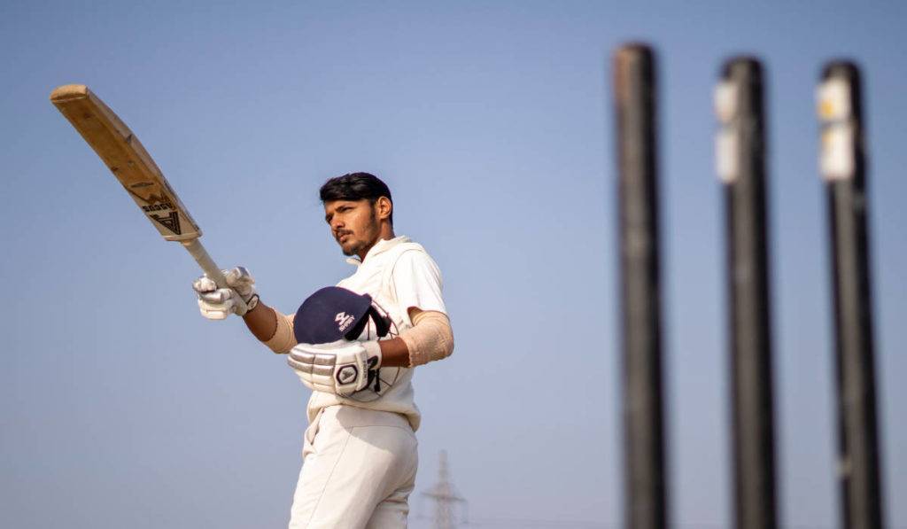 Cricket player with paddle holding helmet - social media marketing 