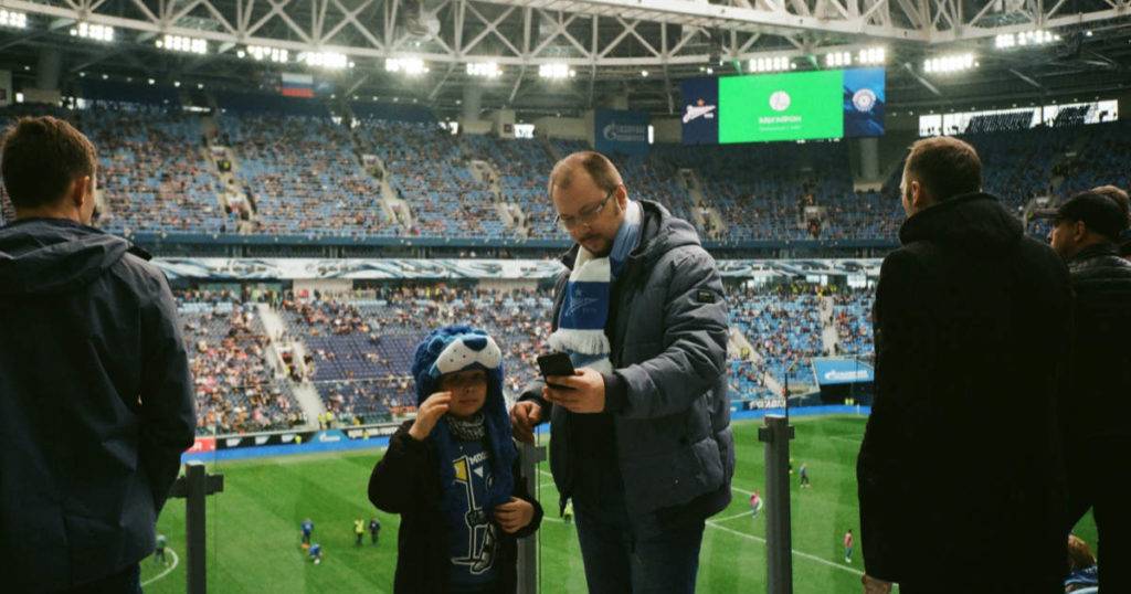 Man and boy at sports event looking at phone; best DAM software