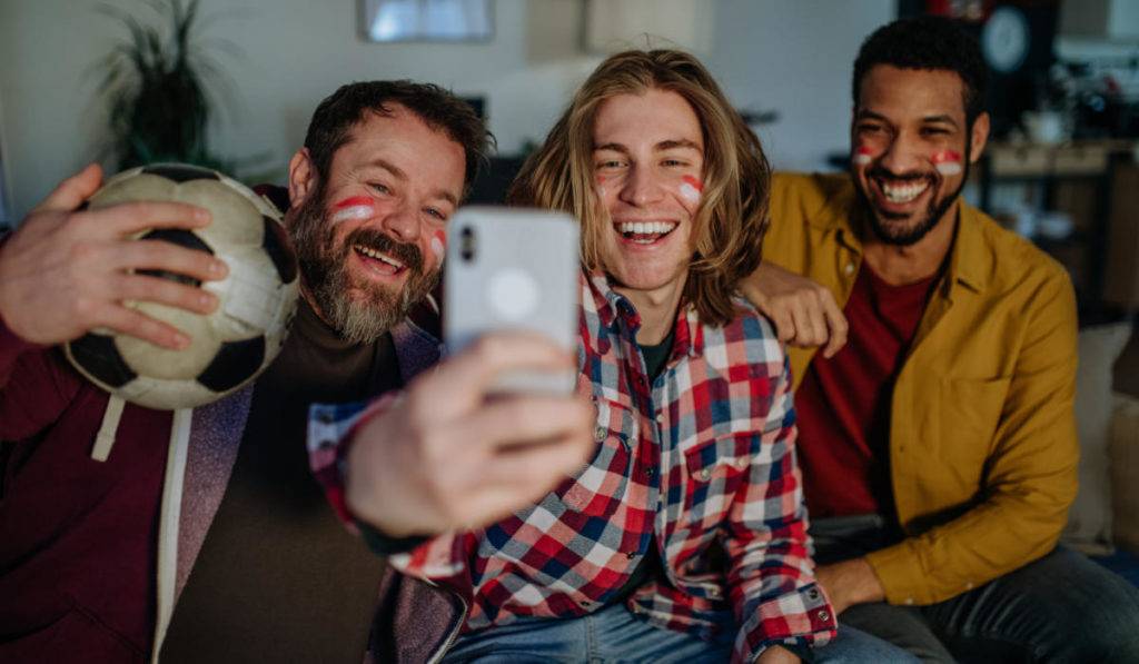 three male soccer fans taking selfie at home as example of best ugc campaigns