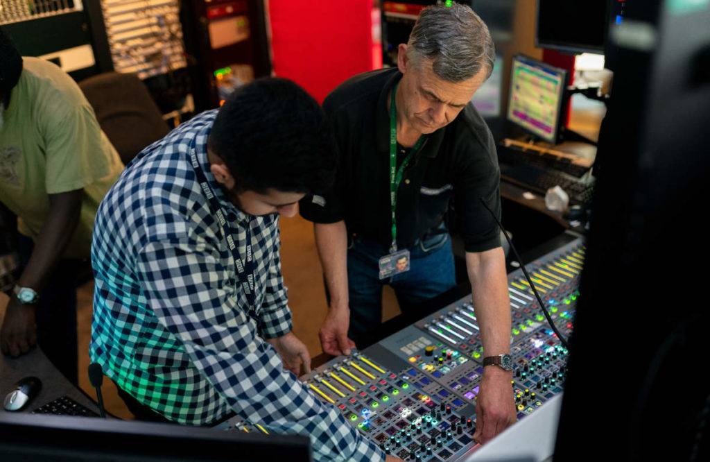 Two engineers in broadcast booth; digital asset manager software