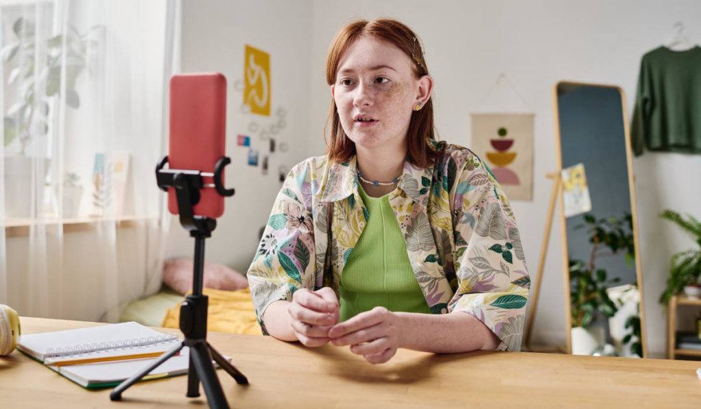 female in front of mobile phone on selfie stand for user generated content