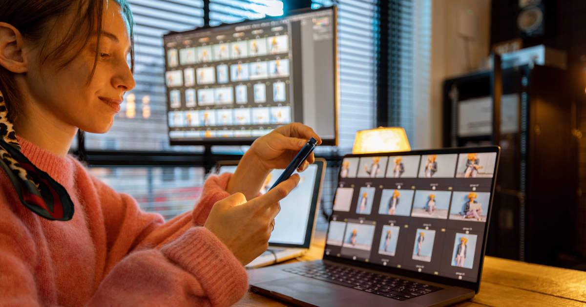 Young creative woman on phone and computers editing DAM vs MAM