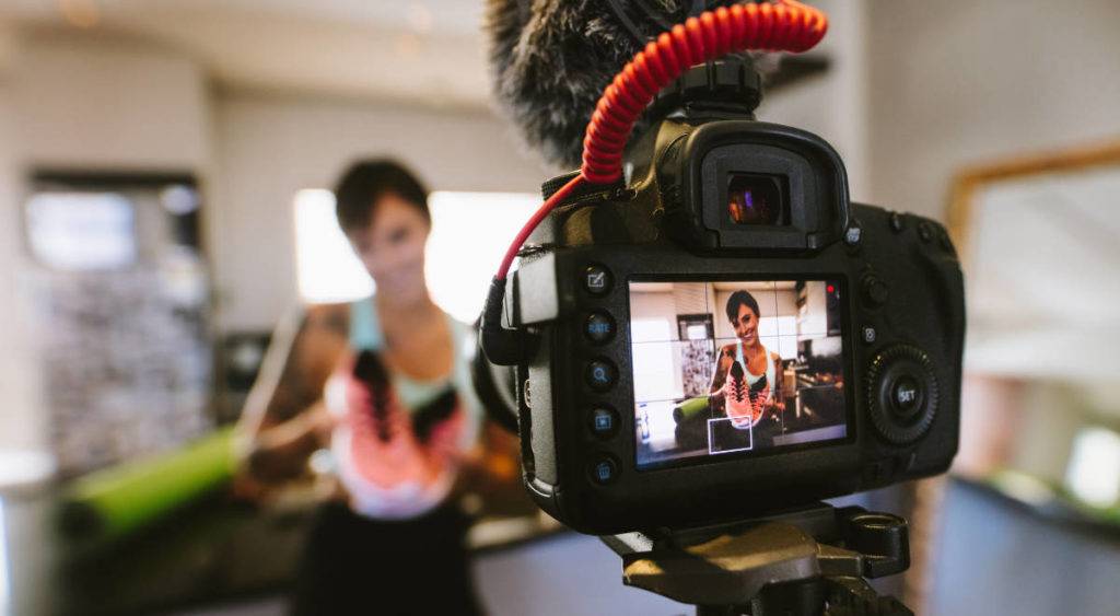 Female video blogger holding sports shoes in front of camera, video saved  in MAM storage