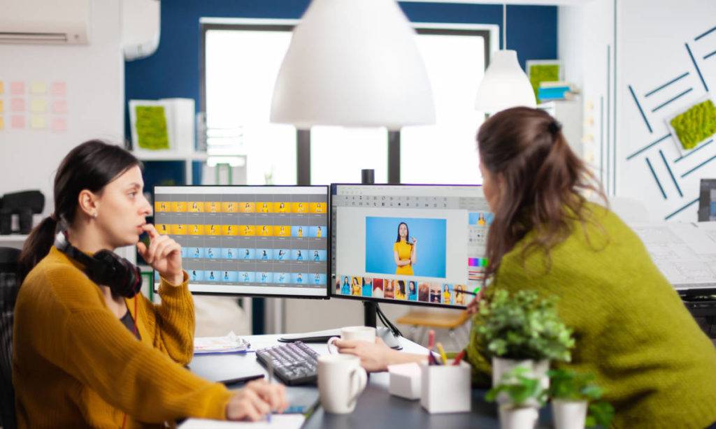 Two female photo editors looking at computer comparing MAM vs DAM