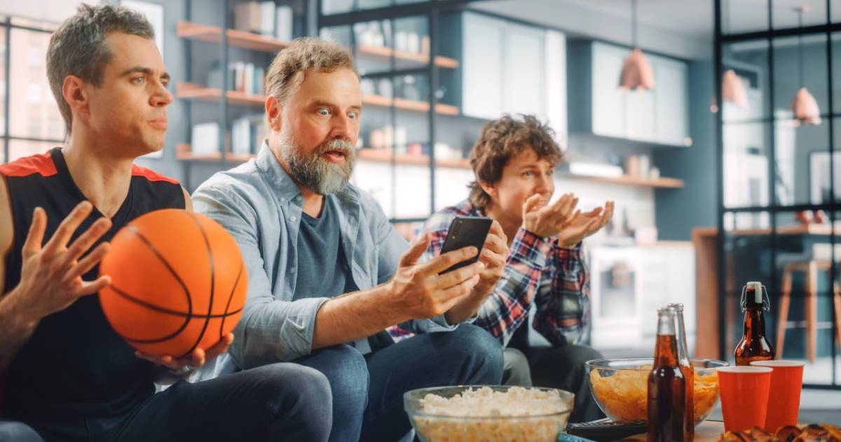 3 male basketball fans watch game on TV and mobile for short form digital media.