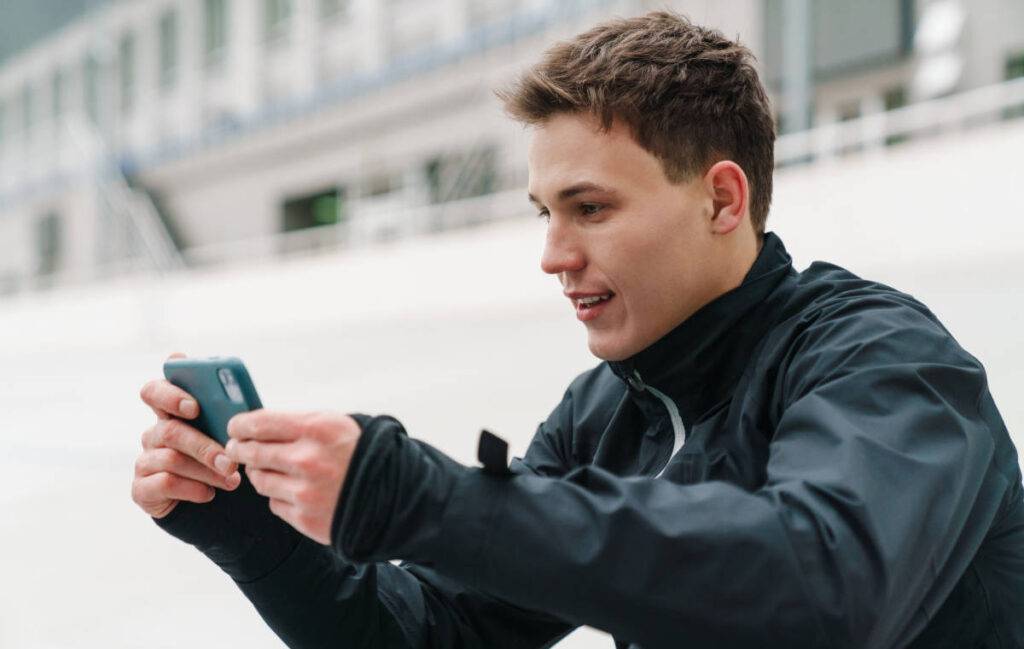 Male looking at his mobile phone in stadium showcasing global fan engagement in sports.