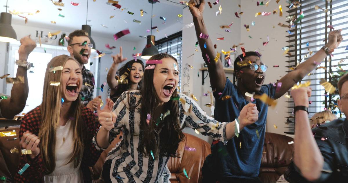 group of people watching game inside and celebrating. Super Bowl marketing with short-form content screens