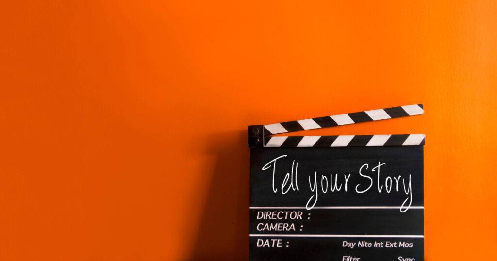clapboard with "Tell Your Story" on it, on orange wall background, for entertainment marketing